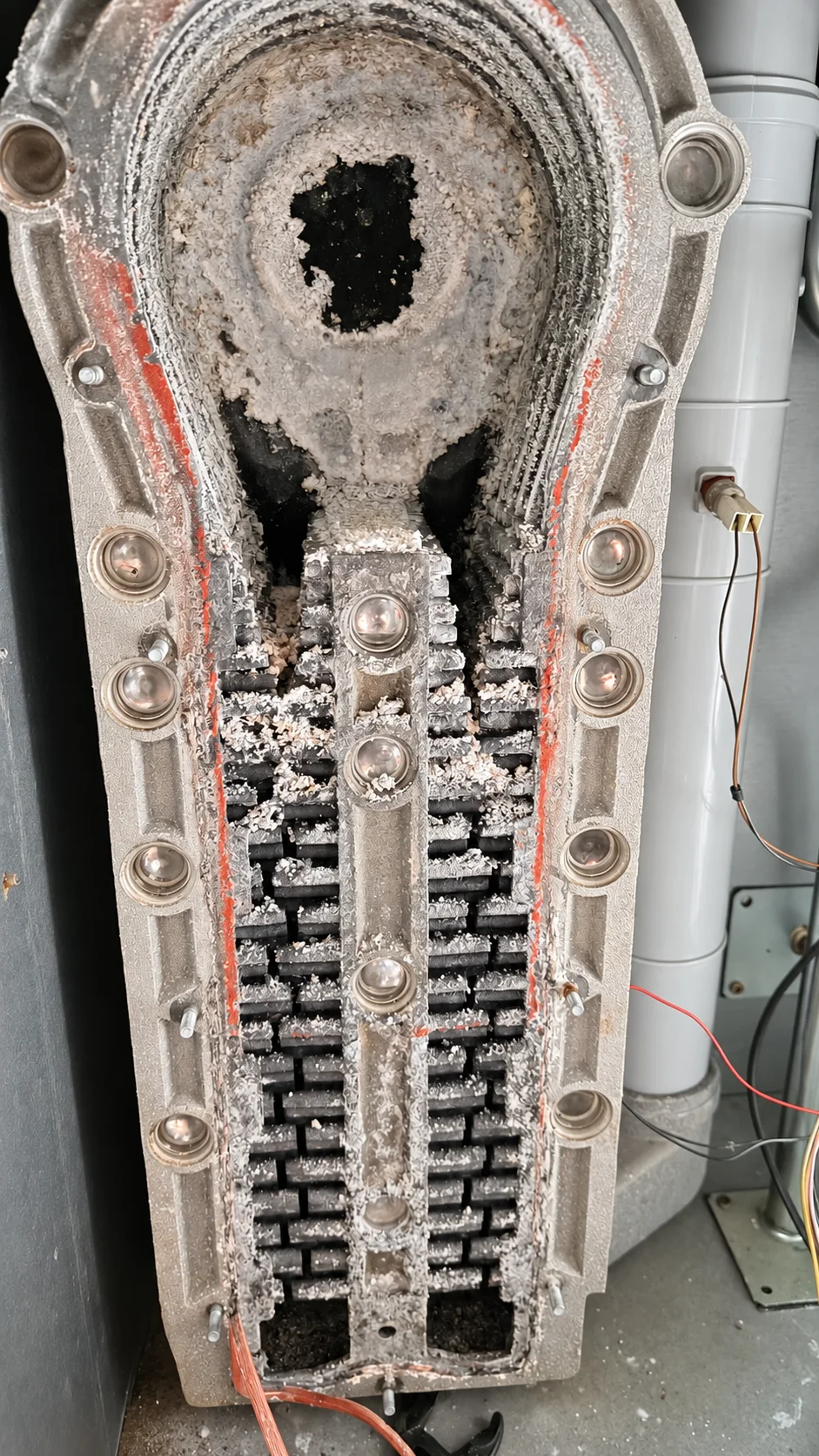 Gros plan sur un corps de chauffe ouvert présentant des dépôts blanchâtres sur les surfaces internes.